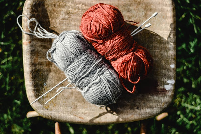 Earthy yarn balls with knitting needles on a rustic chair