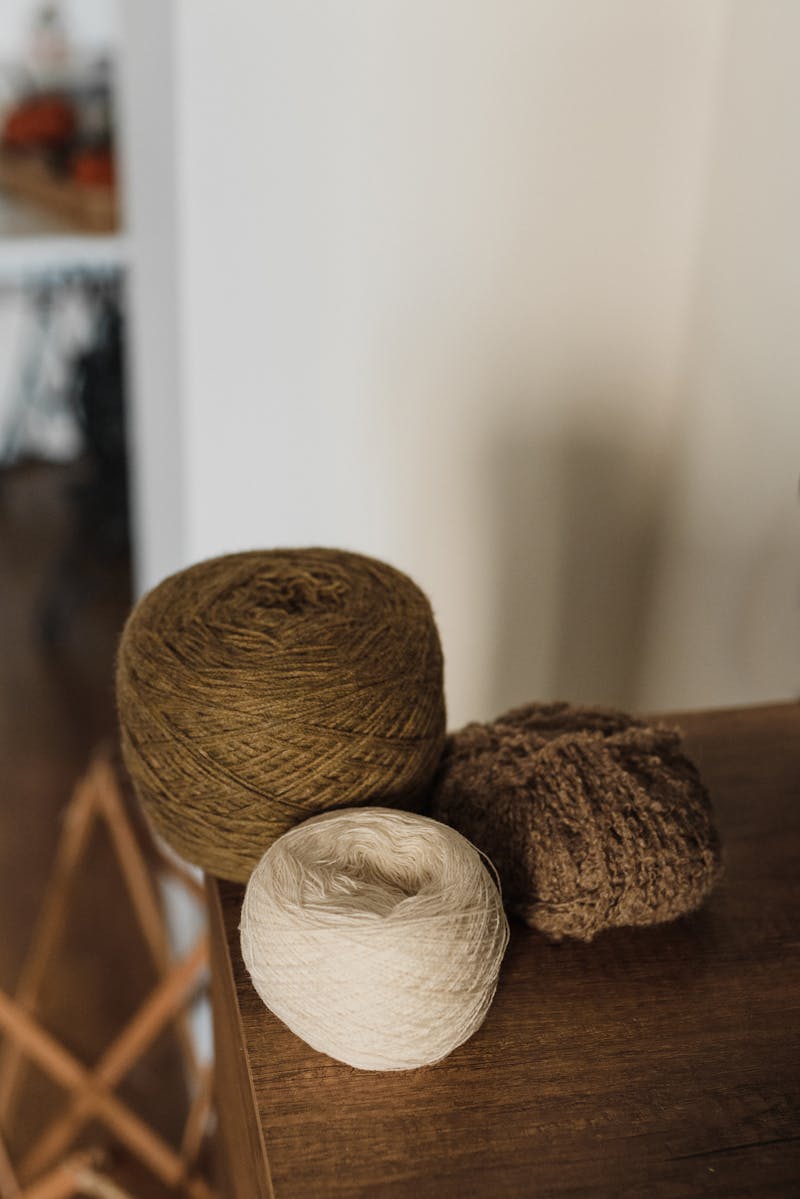 Earthy wool yarn balls on wooden surface